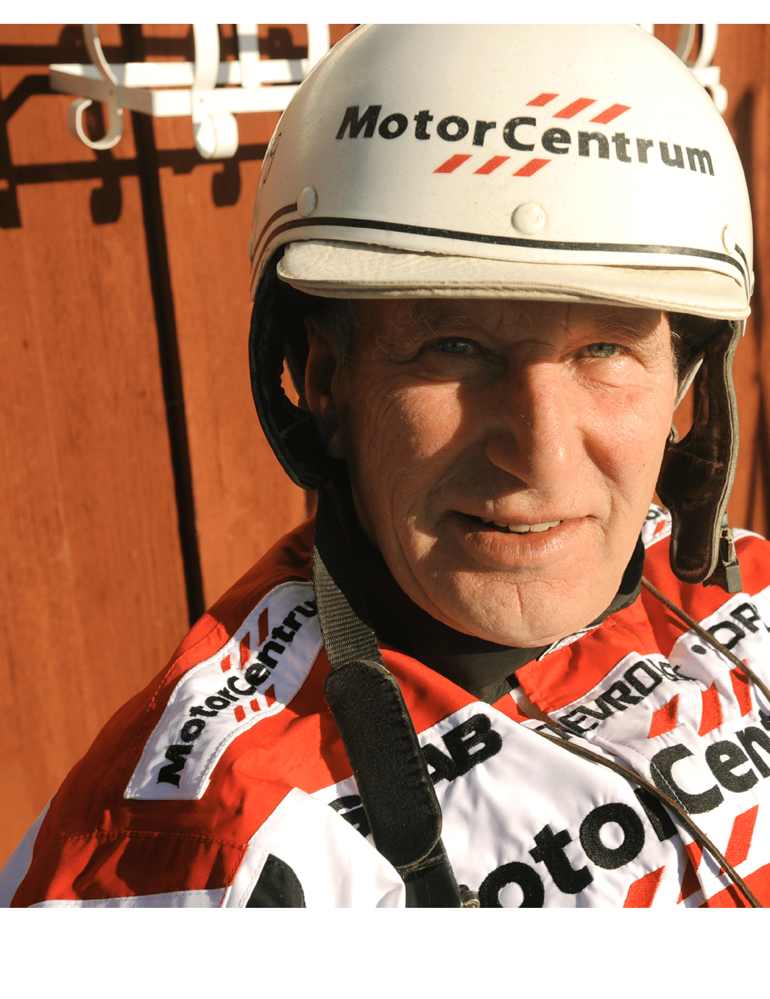 A person wearing a white helmet and a red and white racing suit with the word MotorCentrum printed on both. Description generated by AI